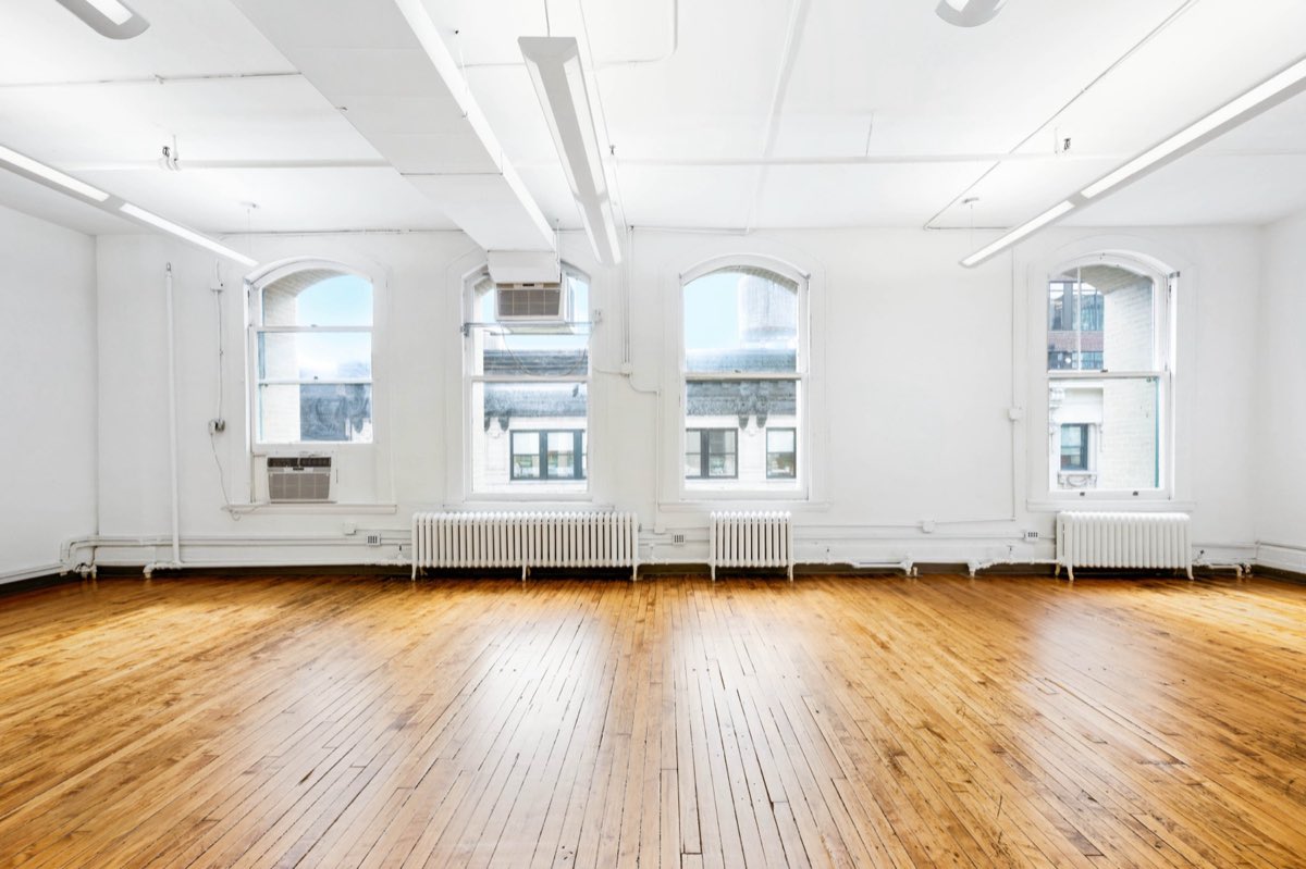 Open loft with arched windows and hardwood floors